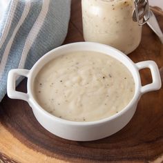 there is a bowl of soup and a jar of sauce on the table next to it