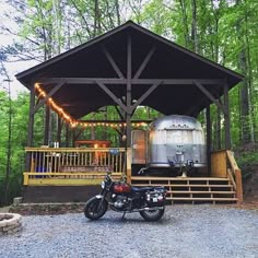 a motorcycle is parked in front of a covered area with lights on the porch and trees