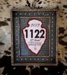 a black and white photo frame with the date on it's side, in front of a cow print background