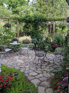 an outdoor patio with tables and chairs surrounded by flowers