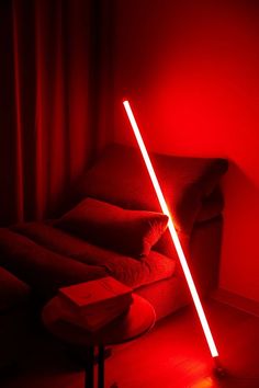 a red room with a light saber on the floor next to a couch and table