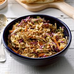 a bowl filled with coleslaw next to some bread