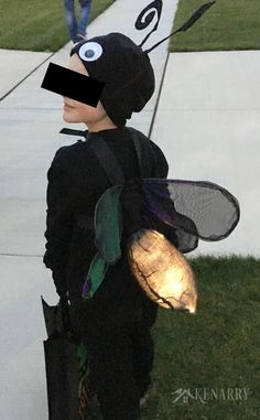 a young boy dressed as a bug holding a tennis racquet in his hand