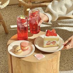 two plates with desserts on them sitting on a table next to drinks and strawberries