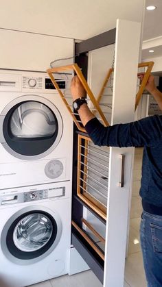 a man is looking into a washer and dryer