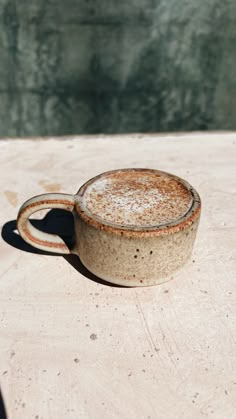 a brown cup sitting on top of a wooden table next to a body of water