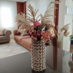 a vase filled with lots of flowers on top of a table next to a couch