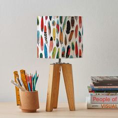 a lamp that is sitting on top of a table next to books and pencils