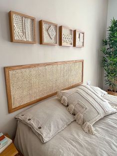 a bed with white linens and pillows in a bedroom next to a potted plant