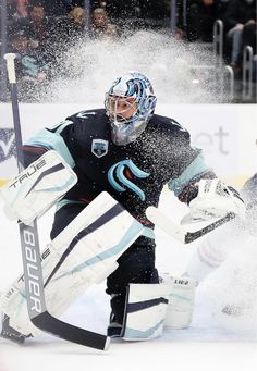 an ice hockey goalie getting ready to make contact with the puck