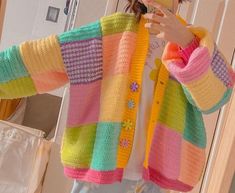 a woman is taking a selfie in the mirror wearing a multicolored cardigan