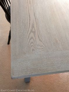 a wooden table with black chairs and a light colored wood grained surface on the floor