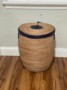 an empty basket sitting on the floor in front of a window with a blue lid