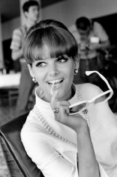 a black and white photo of a woman holding a pair of glasses in front of her face