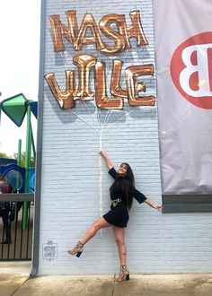 a woman posing in front of a wall with the words wash vile on it