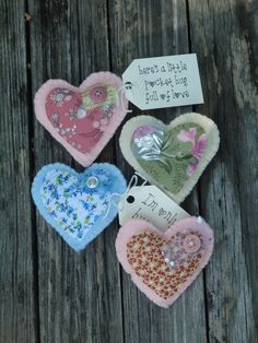 three hearts with tags attached to them sitting on a wooden table next to a sign