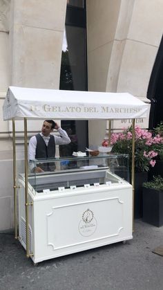 a man standing behind a white counter in front of a building