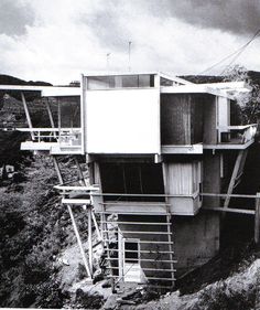 a black and white photo of a house on the side of a hill