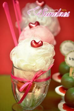 three desserts in glass cups with pink and green candies on the table next to them