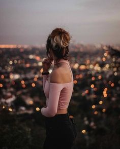 a woman standing in front of a cityscape with her back to the camera