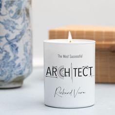 a white candle sitting on top of a table next to a blue and white vase