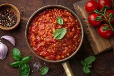 a pan filled with tomato sauce next to garlic and tomatoes