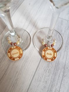 two wine glasses sitting on top of a wooden table next to each other with charms