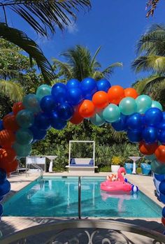 an outdoor pool decorated with blue, orange and white balloons