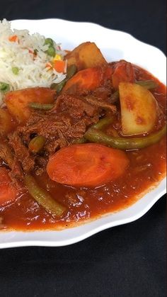 a white plate topped with meat and veggies covered in gravy next to rice