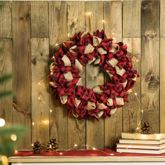 a red and white wreath sitting on top of a wooden wall next to bookshelves