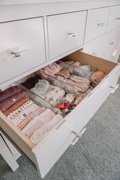 an open drawer with clothes in it on the floor