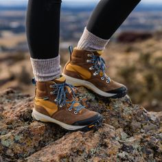 a person standing on top of a rock wearing hiking shoes