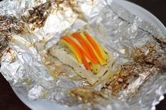 a piece of food that is sitting on tin foil with carrots and other toppings