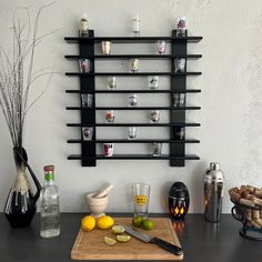 a cutting board with lemons, limes and bottles on the wall behind it