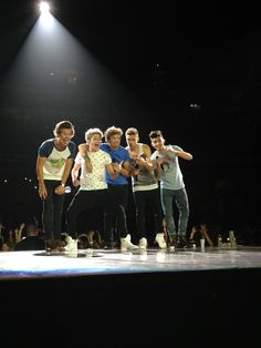 a group of young men standing on top of a stage next to each other in front of a crowd