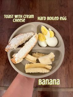 a person holding a plate with bananas, eggs and bread in it that says banana toast with cream hard boiled egg cheese