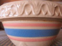 a white bowl with blue, pink and orange stripes sitting on top of a table