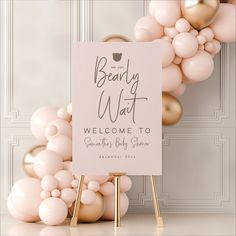 a welcome sign surrounded by balloons in front of a white wall with gold trimmings