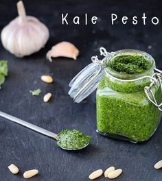 a jar filled with green pesto next to garlic