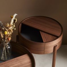 a vase with dried flowers sitting on top of a wooden table next to a glass container