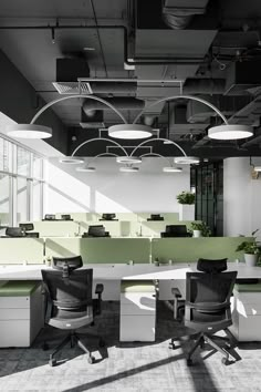 an office with green and white desks, chairs and plant in the middle of the room