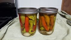 two mason jars filled with pickled vegetables on a towel