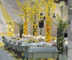 a buffet table with lemons, bananas and candles in vases on the tables