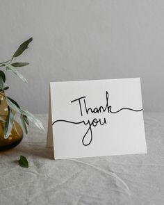 a thank you card sitting on top of a table next to a potted plant