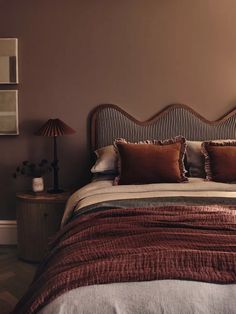 a bed with pillows and blankets on top of it in a bedroom next to two lamps