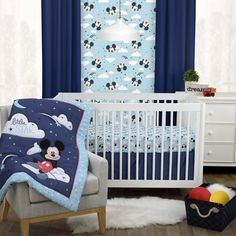 a mickey mouse crib bedding set in a child's room with blue curtains