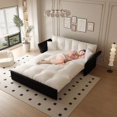 a woman laying on top of a white couch in a living room