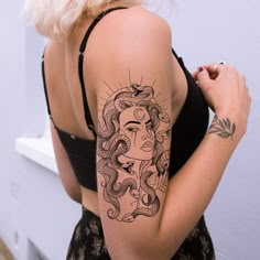 a woman with a snake tattoo on her arm and shoulder is standing in front of a white wall