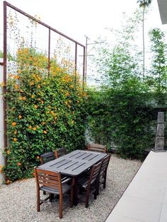 an outdoor dining table and chairs in the middle of a graveled area next to a fence