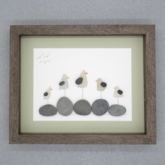 three seagulls sitting on top of rocks in a shadow box with a white background